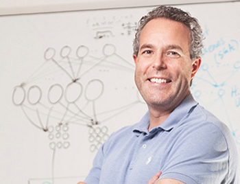 Photograph of ECE Professor Brendan Frey in front of whiteboard