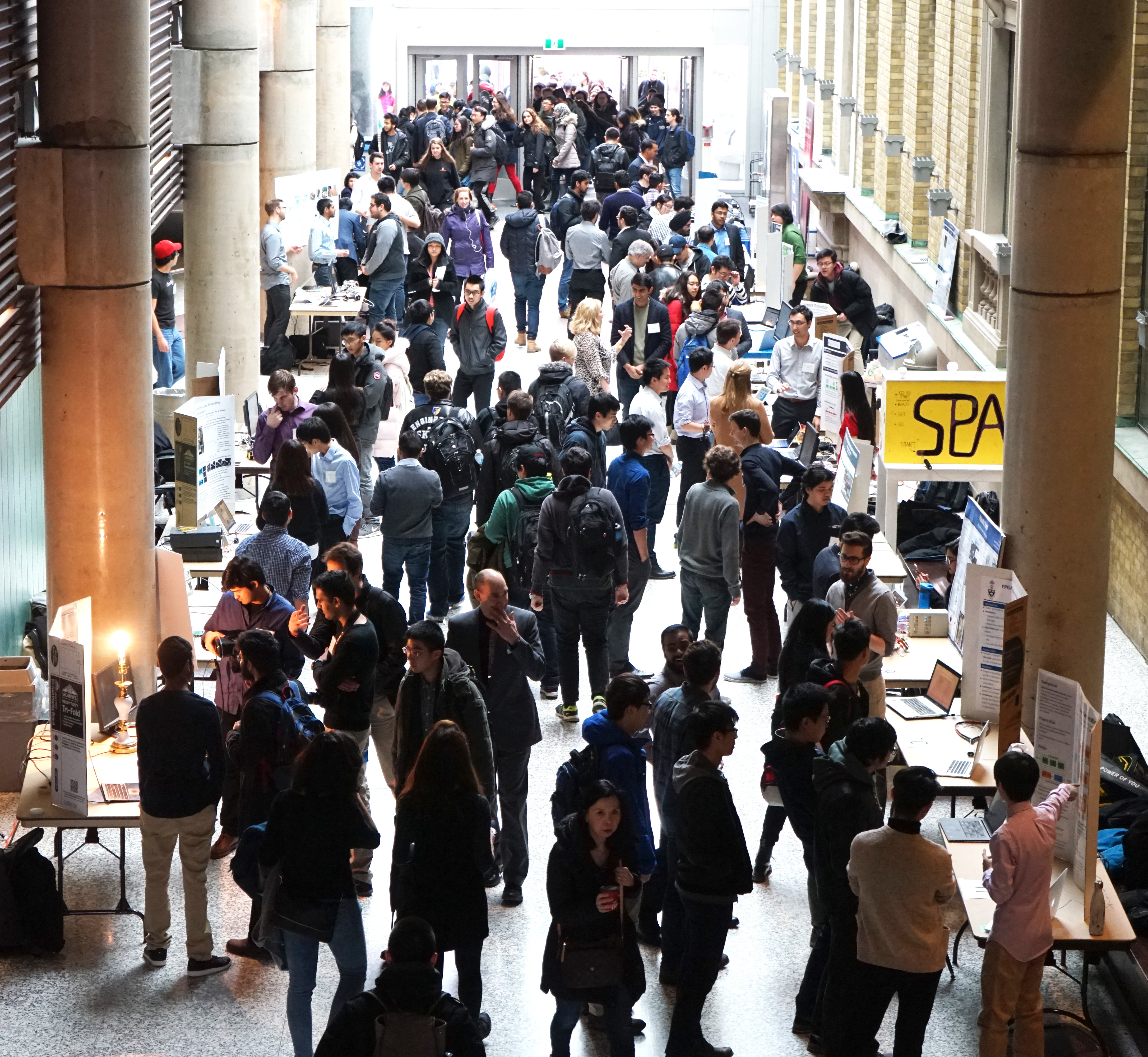 Crowd of people looking at projects in the Bahen Centre for Information Technology.