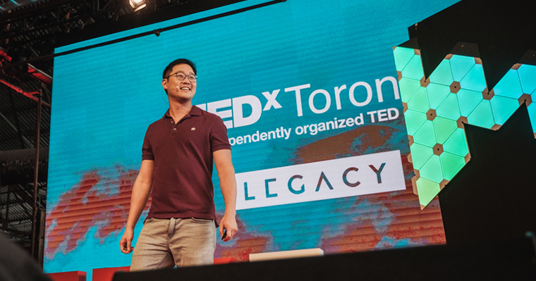 Gimmy Chu stands on stage in front of a TEDX projection