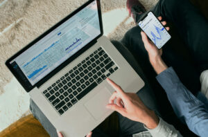 Person pointing at laptop screen displaying financial market data