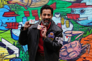 Man holding individual samples of ice cream, graffitied wall in backgroun