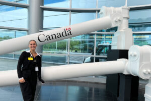 Student posing in front of Air Canadarm in lobby