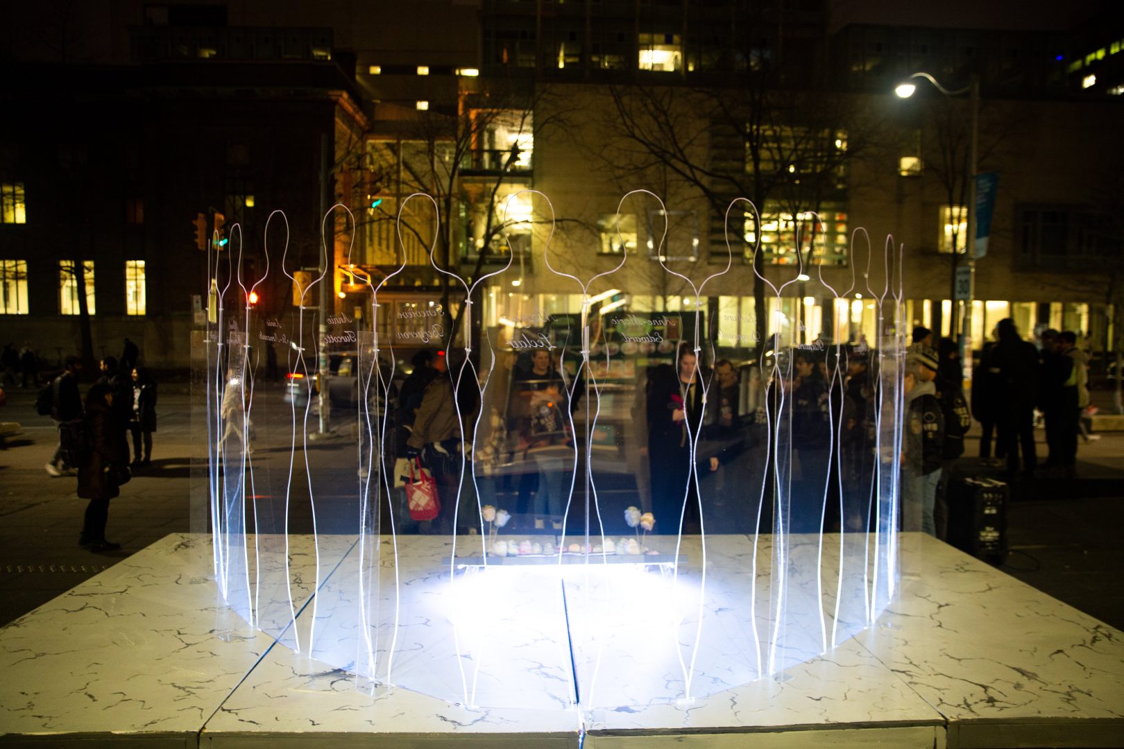 Faint blue silhouettes of women lit up at night