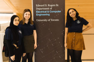 Three women standing beside sign with department's name