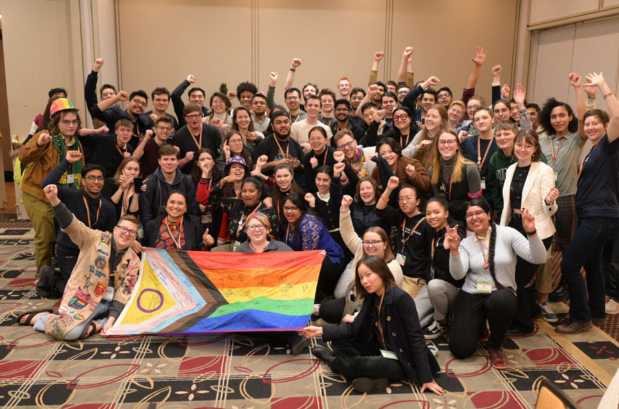 Students, some with arms raised, cheering in a group shot