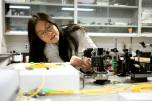 Professor leaning over, adjusting lab equipment