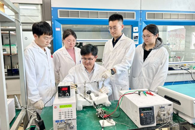 Researchers in lab coats standing around equipment