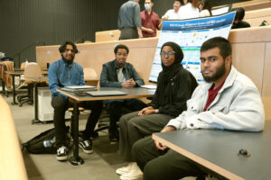 Four students in semi-circle with project board between them