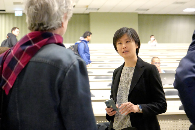 Professor Poon facing entrance inside tiered lecture hall