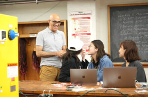 Professor standing next to three students who are looking up at him