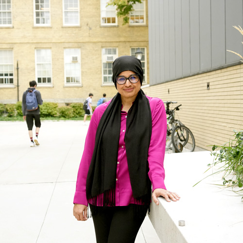 Woman leaning against raised garden bed behind engineering building