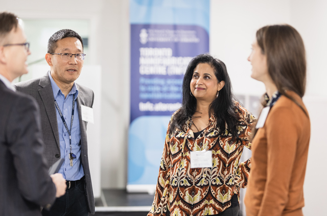 Four people gathered chatting with event floor banner in background