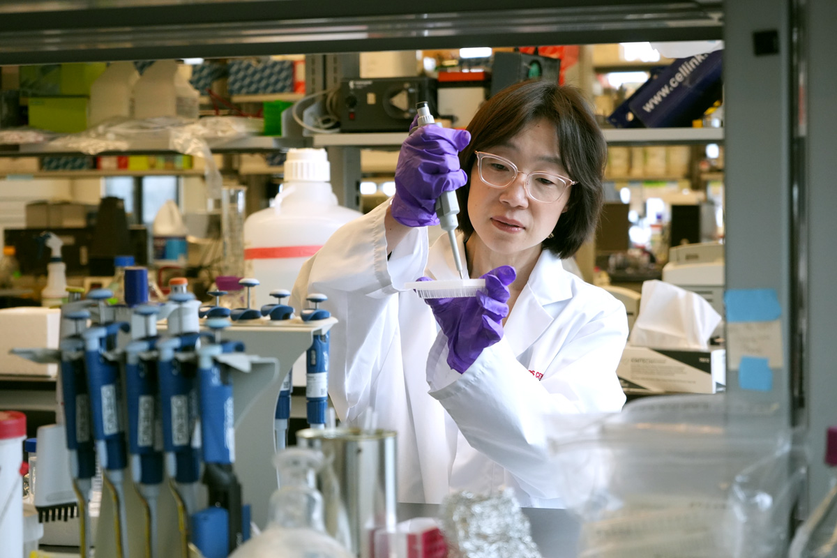 Professor in lab coat concentrates on task surrounded by lab equipment