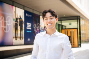 Student smiling in front of engineering building on sunny day