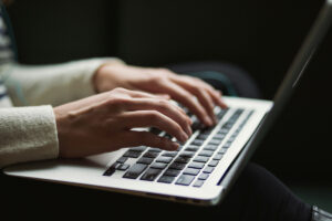 Hands typing on a laptop against shadowed background