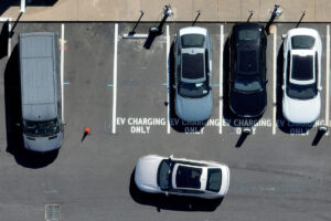 Overhead view of a car turning into a parking space in full lot, with spraypainted EV Parking Only