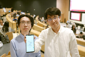 Two students standing, displaying phone with indoor campus map