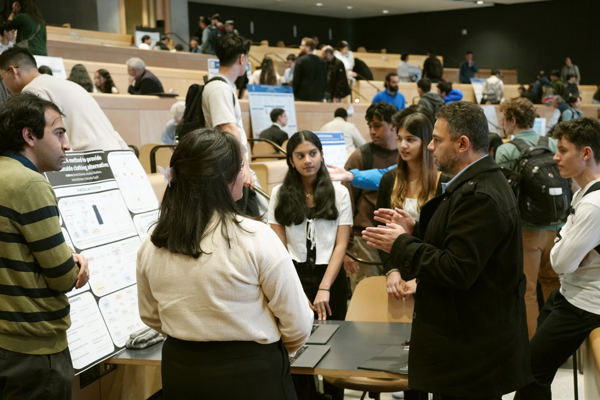 Man gestures to students gathered around a poster board