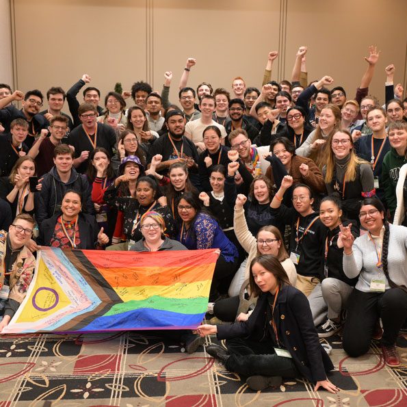 EngiQueers-Conference-900x600-1 Students, some with arms raised, cheering in a group shot